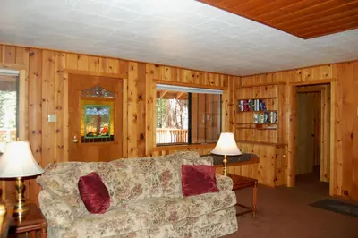 a living room with wooden walls and a couch at 9S Pine Cabin in South Wawona