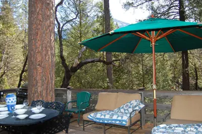 a patio with a table and chairs and an umbrella at 10N Black Oak Lodge in Wawona
