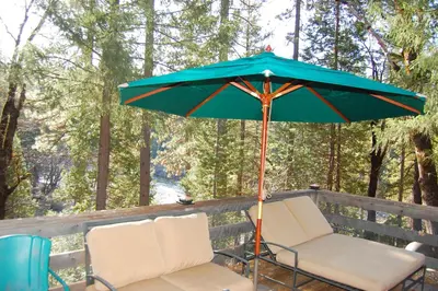 a pair of chairs and an umbrella on a deck at 10N Black Oak Lodge in Wawona