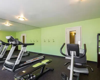 a gym with green walls and tread machines at Hotel Med Park, an Ascend Collection Hotel in Sacramento