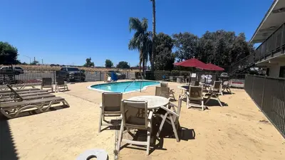 a pool with chairs and a table and an umbrella at Motel 6 Modesto, CA in Modesto