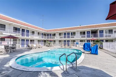 a pool in front of a hotel with tables and chairs at Motel 6 Modesto, CA in Modesto