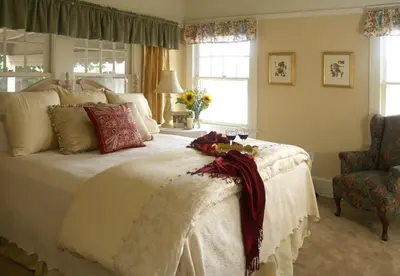 a bedroom with a large white bed and a chair at Cottage on Armstrong in Lodi