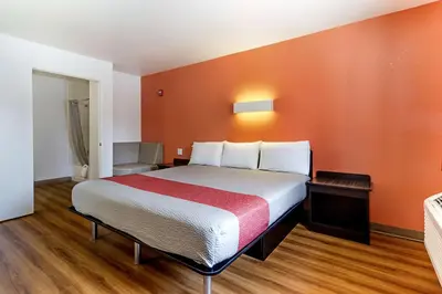 a large bed in a room with orange walls at Motel 6-Fresno, CA in Fresno