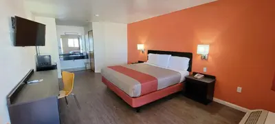 a hotel room with a bed with an orange wall at Motel 6-Santa Nella, CA - Los Banos in Santa Nella Village