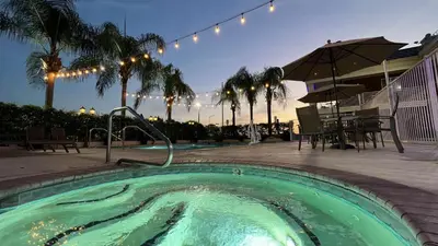 a large swimming pool with a table and umbrella at Best Western Americana in Dinuba
