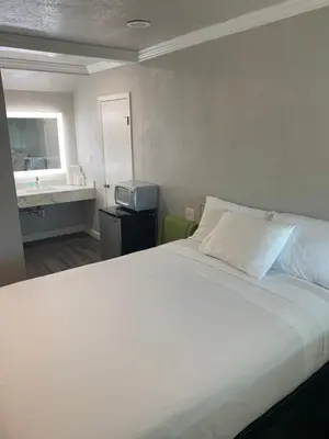 a bedroom with a large white bed and a sink at Elmwood Motel in Auburn