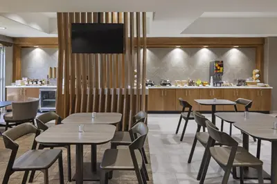 a restaurant with tables and chairs and a kitchen at SpringHill Suites by Marriott Turlock in Turlock