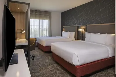 a hotel room with two beds and a flat screen tv at SpringHill Suites by Marriott Turlock in Turlock
