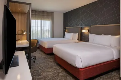 a hotel room with two beds and a flat screen tv at SpringHill Suites by Marriott Turlock in Turlock