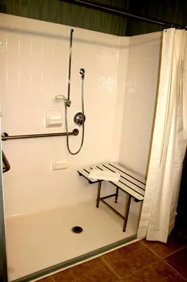 a bathroom with a shower and a bench next to a tub at Hampton Inn & Suites Folsom in Folsom