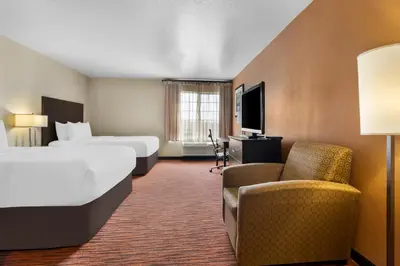 a hotel room with two beds and a chair at Comfort Suites Clovis - Fresno in Clovis