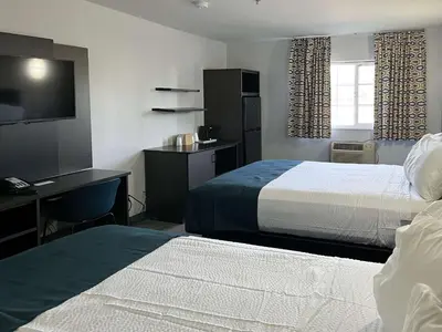 a hotel room with two beds and a desk and a television at Studio 6 Suites Delano, CA in Delano
