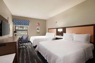 a hotel room with two beds and a desk and a television at Hampton Inn Tracy in Tracy