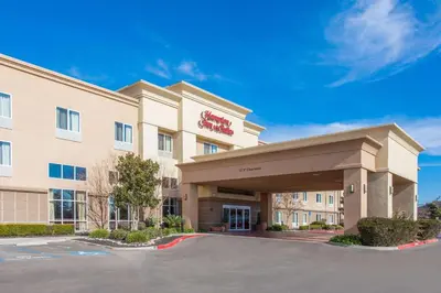 a hotel with a sign on the front of a building at Hampton Inn and Suites Merced in Merced