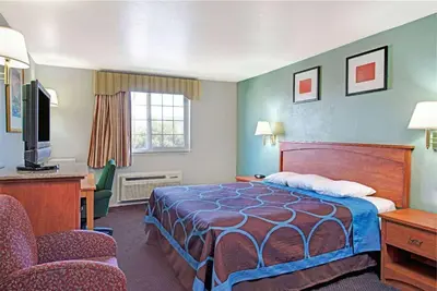 a hotel room with a bed and a desk and chairs at Super 8 by Wyndham Sacramento/Florin Rd in Sacramento
