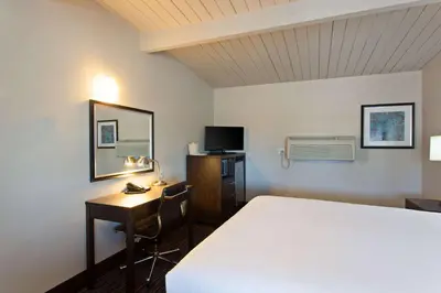 a hotel room with a bed and a desk and a computer at Days Inn by Wyndham Chowchilla Gateway to Yosemite in Chowchilla