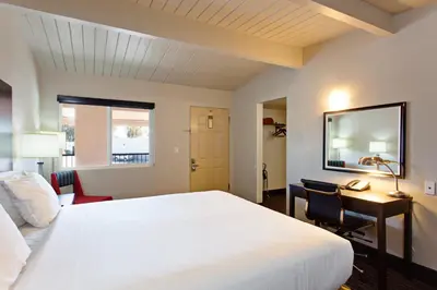 a bedroom with a white bed and a desk and a window at Days Inn by Wyndham Chowchilla Gateway to Yosemite in Chowchilla