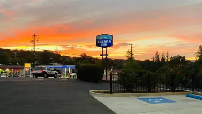 a gas station sign in a parking lot with a sunset at Sierra Inn in San Andreas