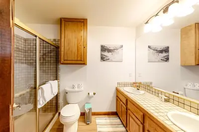 a bathroom with a toilet and two sinks and a shower at Mammoth Pines 11 in Mammoth Lakes