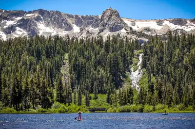 two people in a lake in front of a mountain at Mammoth Pines 11 in Mammoth Lakes