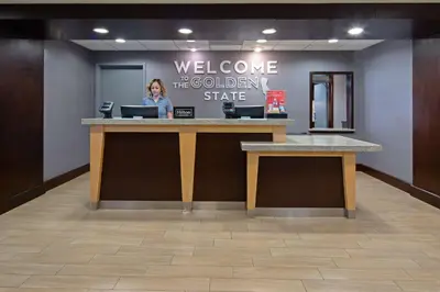 a woman standing at a welcome counter in a lobby at Hampton Inn Visalia in Visalia