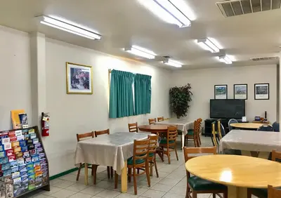 a dining room with tables and chairs and a flat screen tv at Sunrise Inn in Turlock