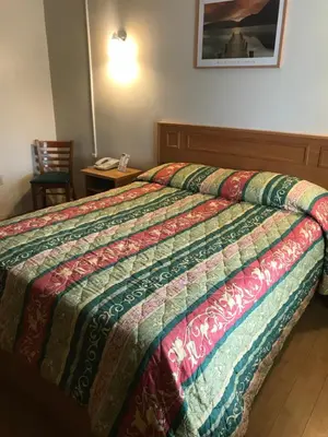 a bed in a hotel room with a quilt on it at Sunrise Inn in Turlock