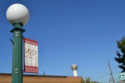 a sign on a street light with a water tower in the background at Days Inn & Suites by Wyndham Lodi in Lodi