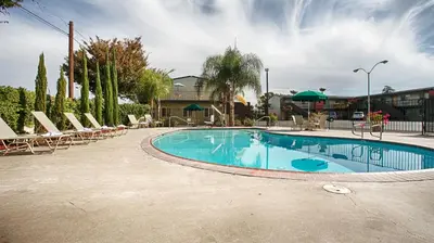 a large swimming pool with chairs and umbrellas at Days Inn & Suites by Wyndham Lodi in Lodi