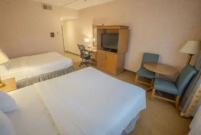 a hotel room with two beds and a table and a television at Piccadilly Inn Airport in Fresno