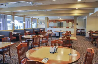 a dining room with tables and chairs and a cafeteria at Piccadilly Inn Airport in Fresno