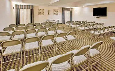 a room with rows of chairs and a flat screen tv at La Quinta by Wyndham Fowler in Fowler