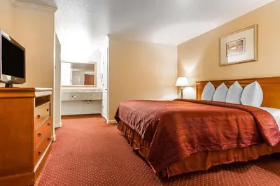 a hotel room with a bed and a flat screen tv at Quality Inn & Suites Gilroy in Gilroy