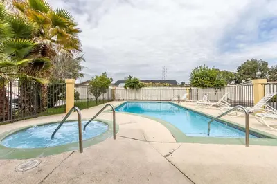 a swimming pool with a fence and a palm tree at Quality Inn & Suites Gilroy in Gilroy
