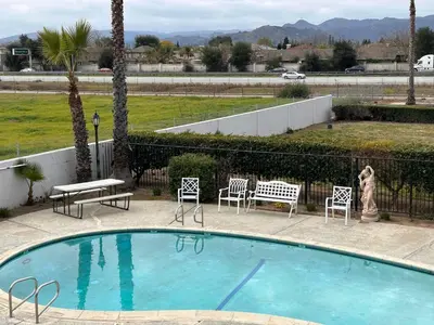 a woman is standing next to a swimming pool at SureStay by Best Western Morgan Hill in Morgan Hill
