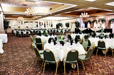 a banquet hall with white tables and green chairs at University Square Hotel in Fresno
