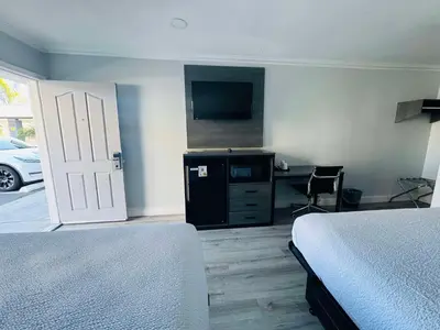 a bedroom with two beds and a tv and a desk at SureStay by Best Western Fresno Central in Fresno