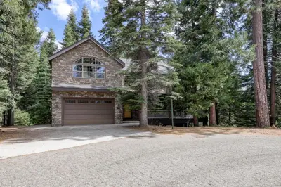 a stone house with a garage in the woods at Alderhill in Shaver Lake