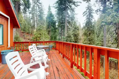a deck with white chairs and a table on it at Deaver's Place in Shaver Lake