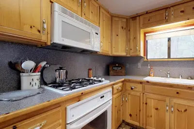 a kitchen with wooden cabinets and a white stove top oven at Foxtail Delight in Dora Belle