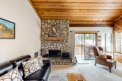 a living room with a leather couch and a stone fireplace at Huntington Lake Condo 92 in Lakeshore