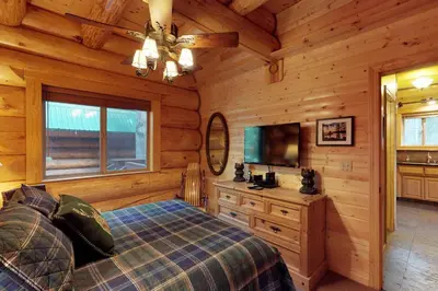 a bedroom with a bed and a television in a log cabin at Loggers Landing in Lakeshore