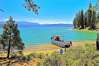 a boat parked on the shore of a lake at Mountain Memories in Shaver Lake