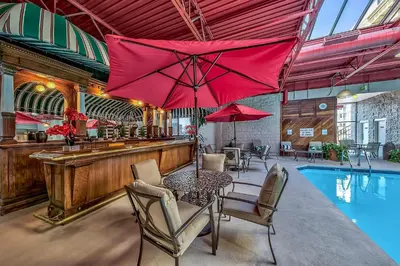 a bar with a table and red umbrellas next to a pool at Plaza Resort Club Reno in Reno