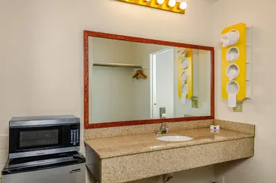 a bathroom with a microwave and a sink with a mirror at Motel 6 Oakdale, Ca in Oakdale