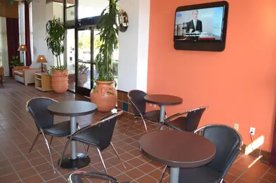 a waiting room with tables and chairs and a tv at Motel 6 Oakdale, Ca in Oakdale