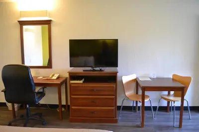 a room with a desk and a tv and a table and chairs at Motel 6 Oakdale, Ca in Oakdale