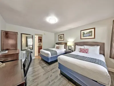 a hotel room with two beds and a desk at Heavenly Inn Lake Tahoe in South Lake Tahoe