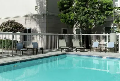 a swimming pool with chairs and a fence at Homewood Suites by Hilton Fresno Airport/Clovis in Clovis